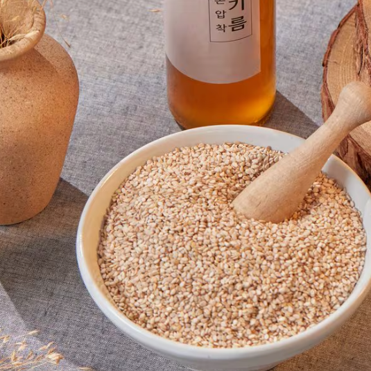 Roasted sesame seeds in white bowl with wooden spoon
