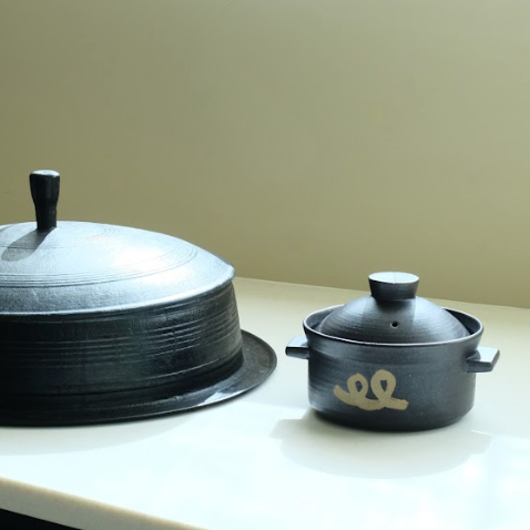 Black rice pot with domed lid and gold logo on tabletop