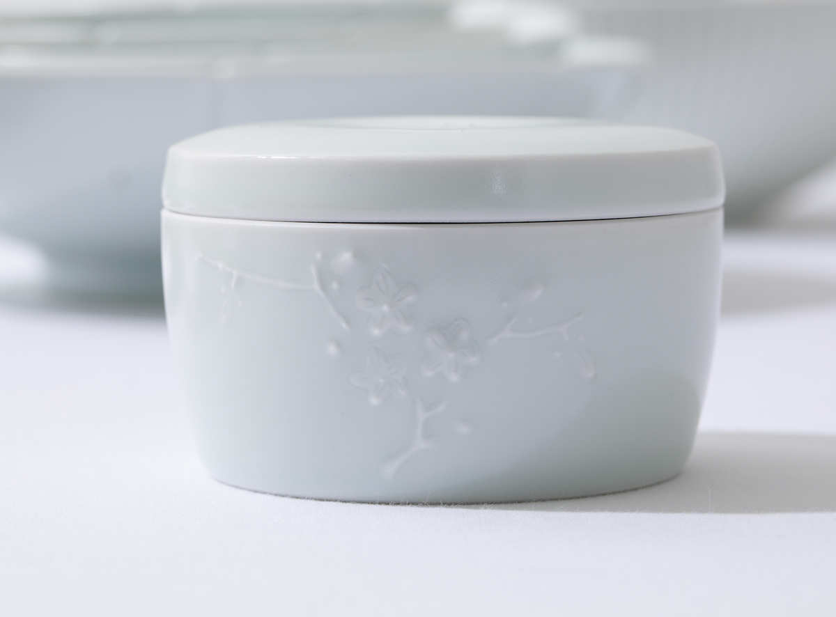 White porcelain lidded container with embossed floral pattern on lid and body