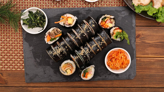 Korean Gimbap sliced on a wooden table with traditional side dishes in natural light