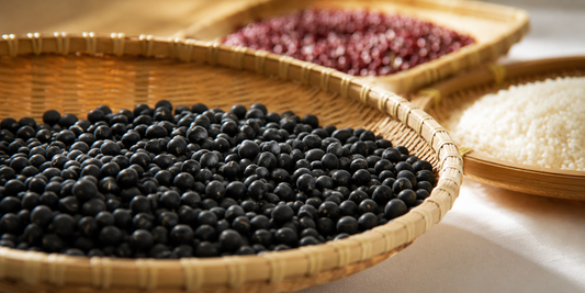 Premium Korean Seoritae black soybeans displayed in traditional woven baskets with rice and red beans, representing Korean wellness food culture and healthy everyday ingredients.