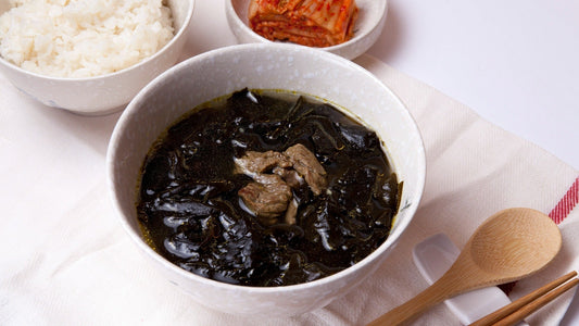 Korean miyeokguk seaweed soup served with rice, kimchi, and traditional chopsticks as a comforting Korean birthday soup.