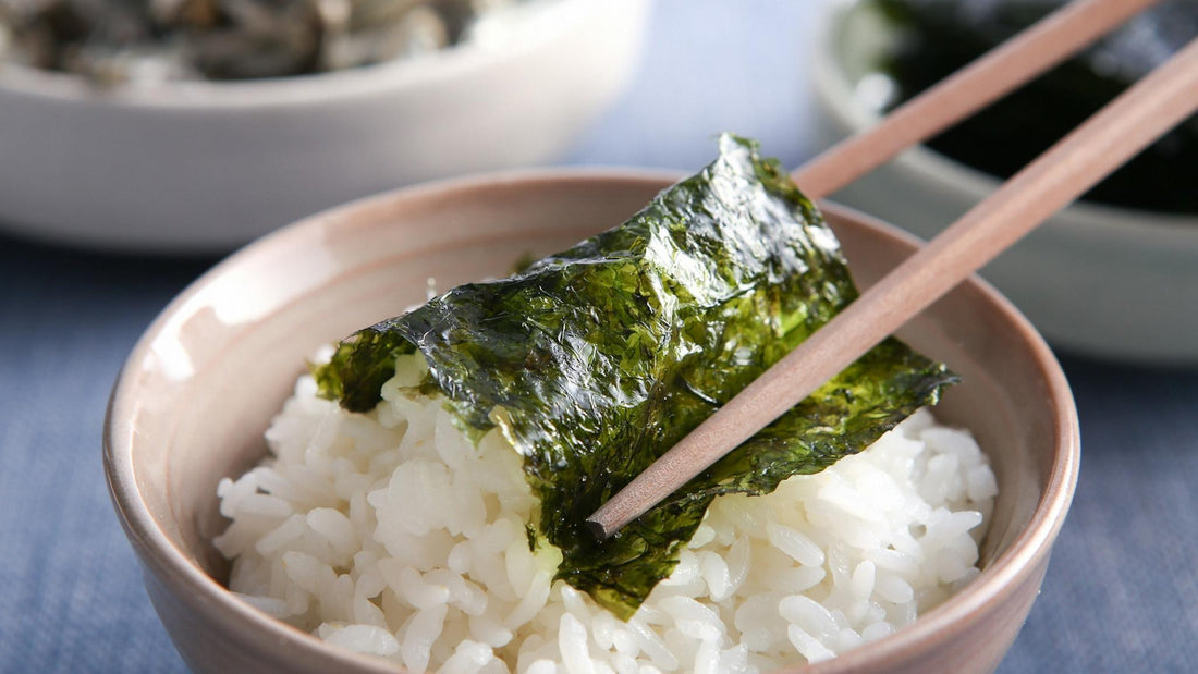 Korean seaweed (gim) being picked up with chopsticks over a bowl of rice, showing a simple traditional Korean meal