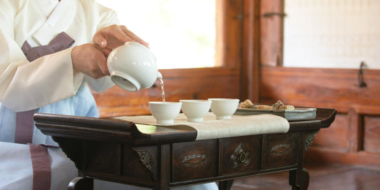 Woman in a traditional Korean hanbok pouring tea during a Korean tea ritual