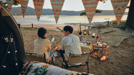 Korean camping scene with cozy tent interior, couple, and outdoor dinner setup by the sea