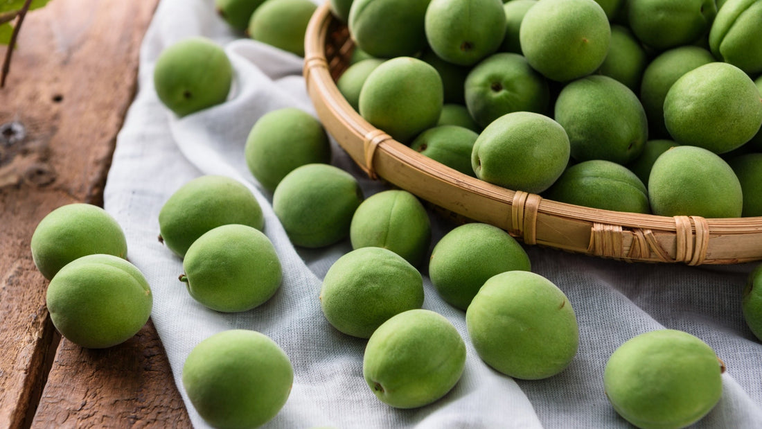 Fresh Korean green plums (maesil) in a bamboo basket, a seasonal ingredient used for maesil extract and Korean cooking