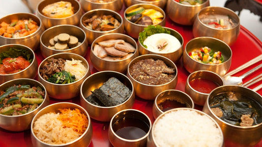 Seollal Korean table setting with steamed rice, soup, and assorted side dishes served in traditional brass bowls.