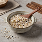 Bowl of organic germinated ten-grain mix with wooden spoon and scattered grains