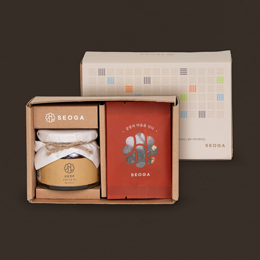 A boxed gift set from SEOGA on a dark brown background. The set includes a kraft paper box with a white jar wrapped in white paper and tied with twine, a red pouch with Korean text and a small illustration, and a tall white box behind it with a colorful grid pattern.