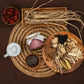 Herbal jar with maroon label on woven mat, surrounded by dried herbs