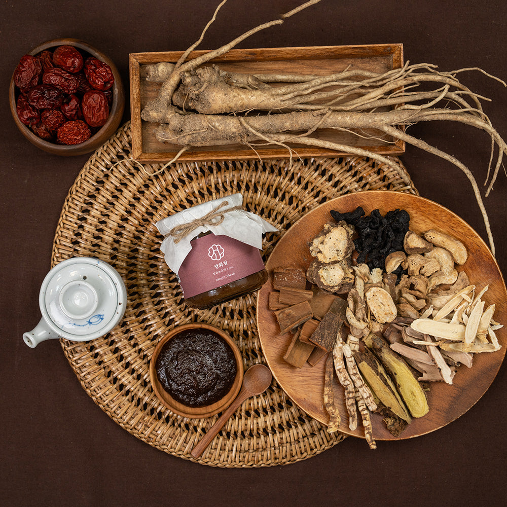 Herbal jar with maroon label on woven mat, surrounded by dried herbs