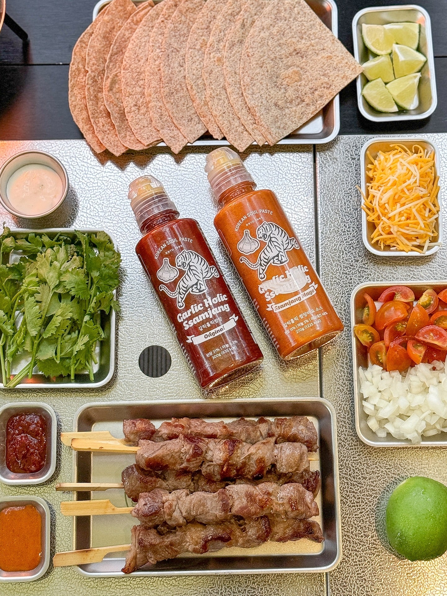 Garlic Holic Ssamjang sauce bottles with grilled skewers and veggie side trays