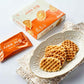 Butter waffles on decorative white plate with box and wrapped snack pack beside