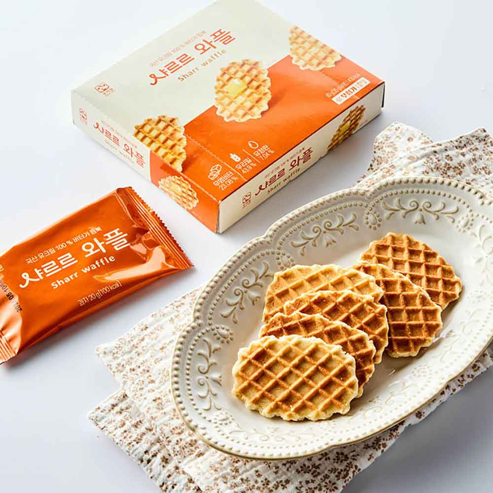 Butter waffles on decorative white plate with box and wrapped snack pack beside