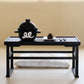 Black ceramic rice pot with lid and white emblem on a serving tray.