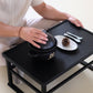 Black ceramic rice pot with lid on a tray, hands setting the lid in place.