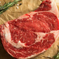 Raw thick steak on parchment with rosemary and black pepper