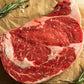 Ribeye steak on parchment with herb sprigs and pepper