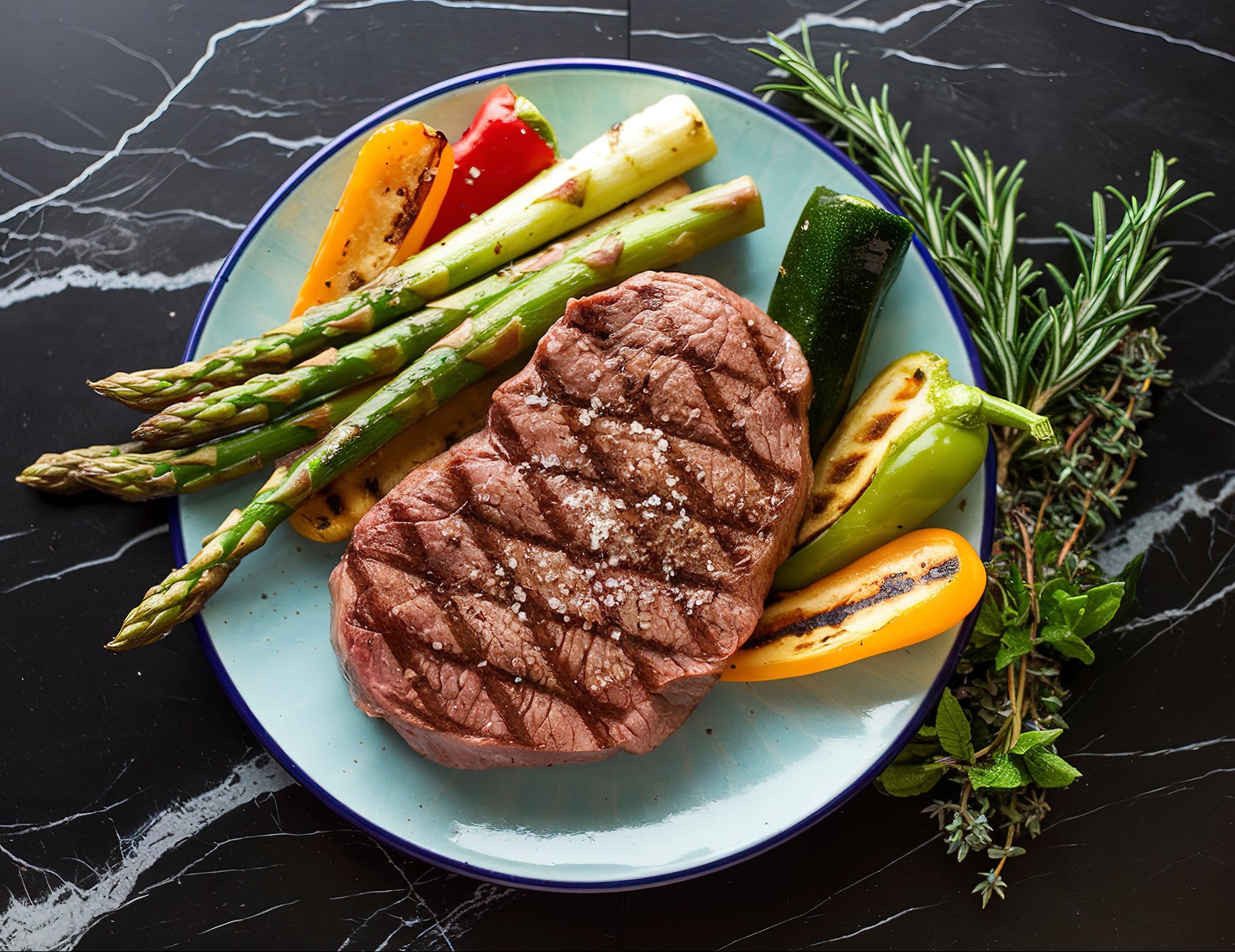 Seared steak slices on a plate with asparagus and mixed vegetables