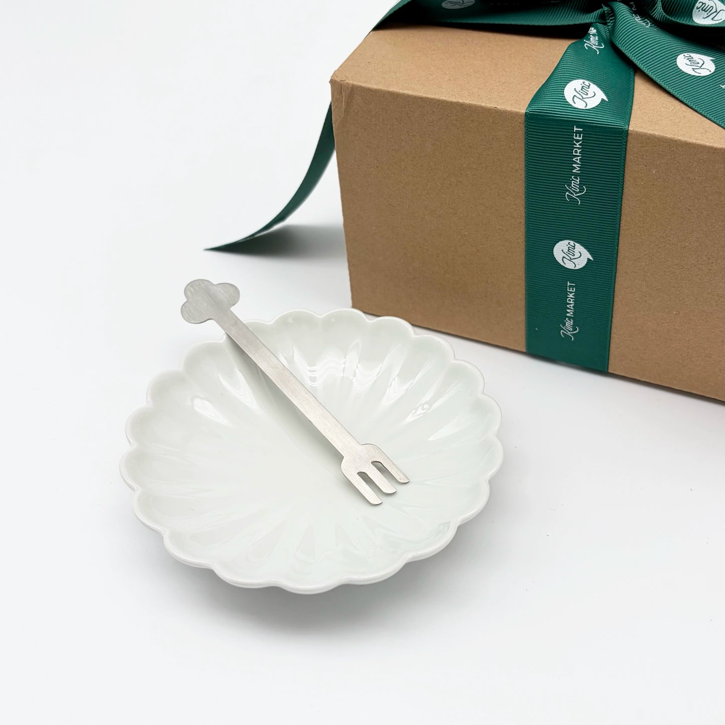 Flower-shaped dessert plate with matching fork resting across it, white ceramic