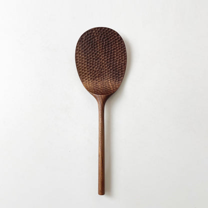 Dark wood rice paddle with textured oval scoop and long handle, standing alone