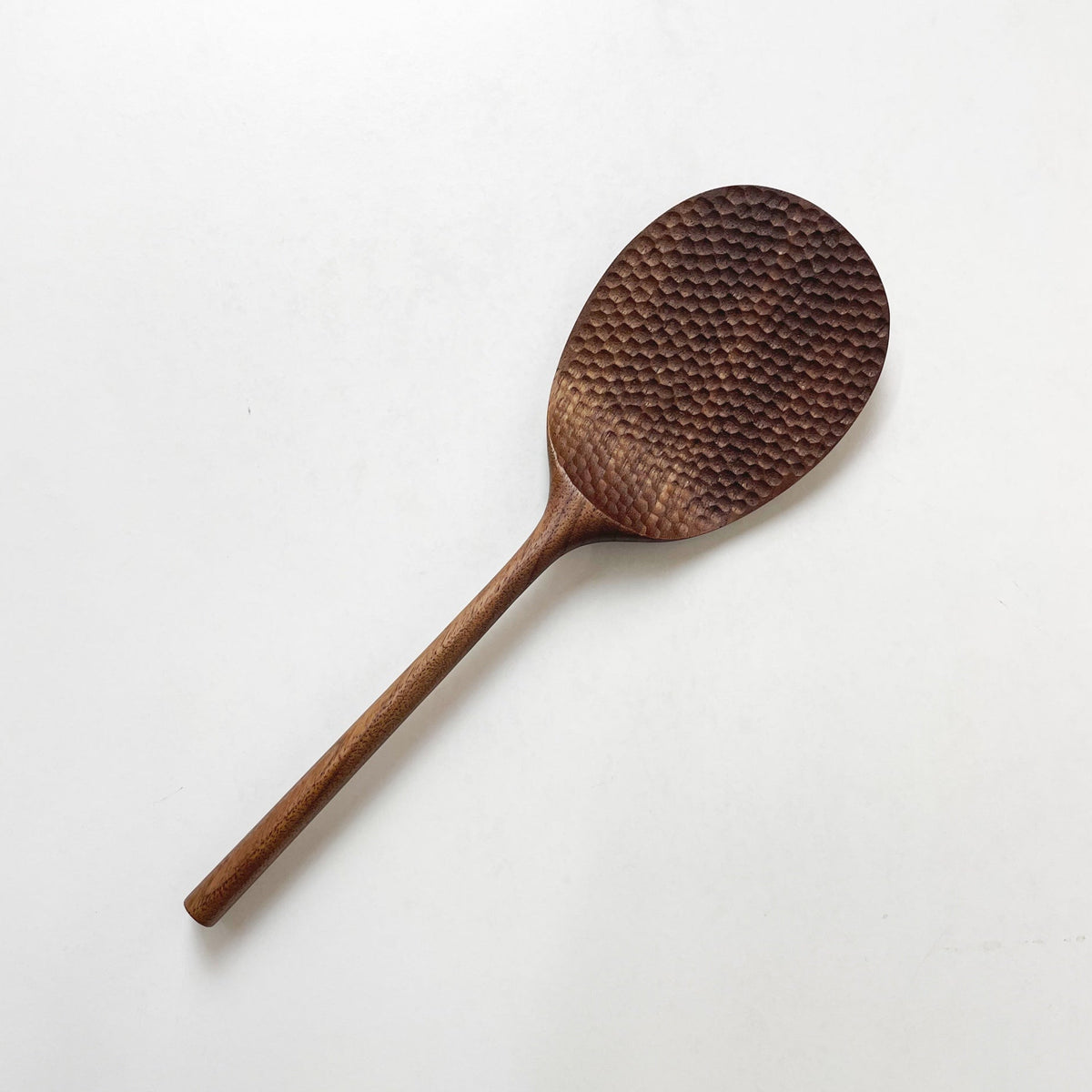 Dark wood rice paddle with textured oval scoop and long handle, angled