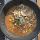 Pan of broth with sliced peppers, onions, and herbs