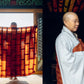 Woman in light robe holding a brown bag indoors near a window with red curtains