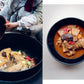 Cooked kimchi stew in a black pot with hands tossing food; side bowl on white