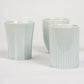 Three pastel blue ceramic cups, two smooth and one with vertical ridges