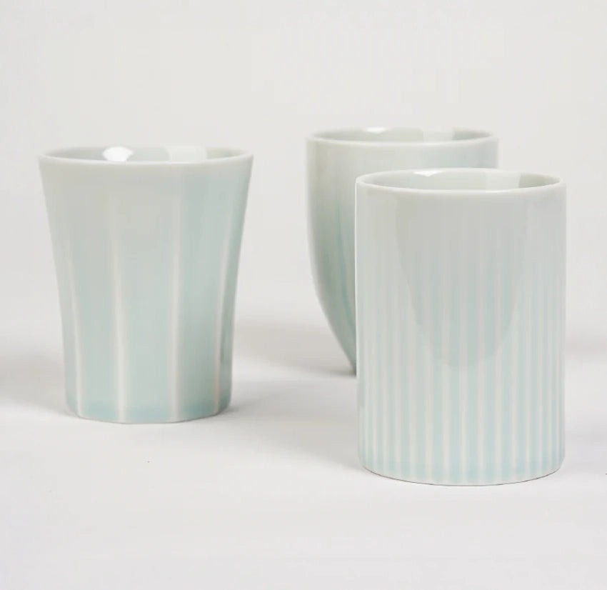 Three pastel blue ceramic cups, two smooth and one with vertical ridges