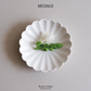 Flower-shaped white dessert plate with herb garnish