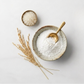 Bowl of white organic rice flour with wooden spoon and rice grains