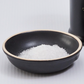 Dark bowl of coarse sea salt with white crystals inside