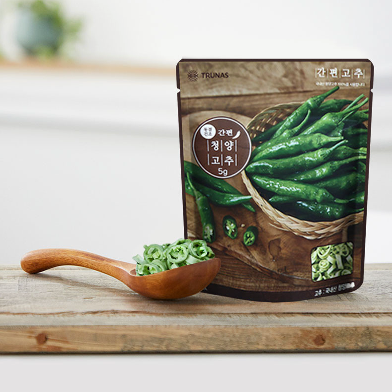 Pack of sliced Cheongyang chili peppers with wooden spoon and sliced green chili pieces