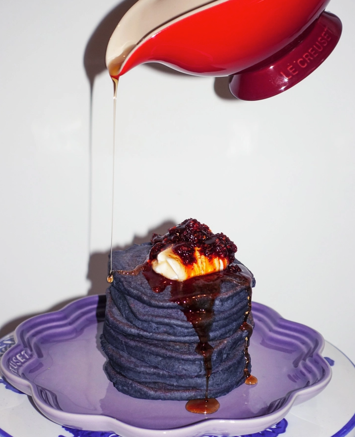 Ube mochi pancake stack with syrup drizzled in purple dish