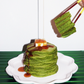 Stack of green mochi pancakes on plate with caramel drizzle and chopsticks