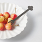 Flower-shaped white dessert plate with matching fork and fruit