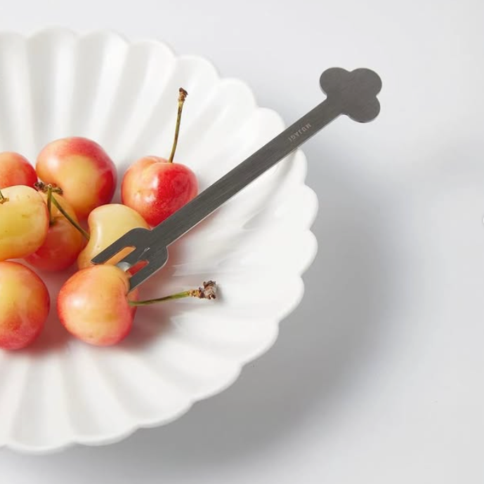 Flower-shaped white dessert plate with matching fork and fruit