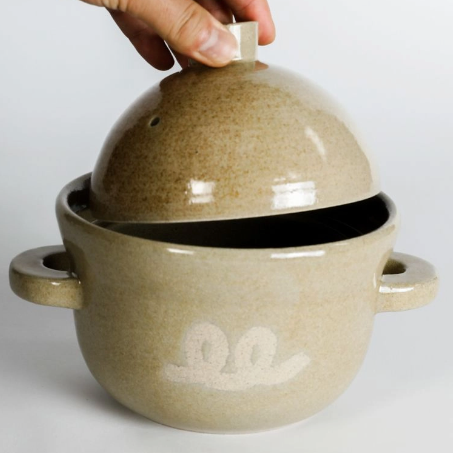 Ceramic rice pot with lid lifted by hand, beige glaze, owl logo and handles