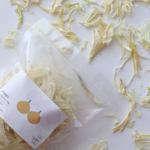 Dried onion flakes spread on white surface, pale yellow thin shreds