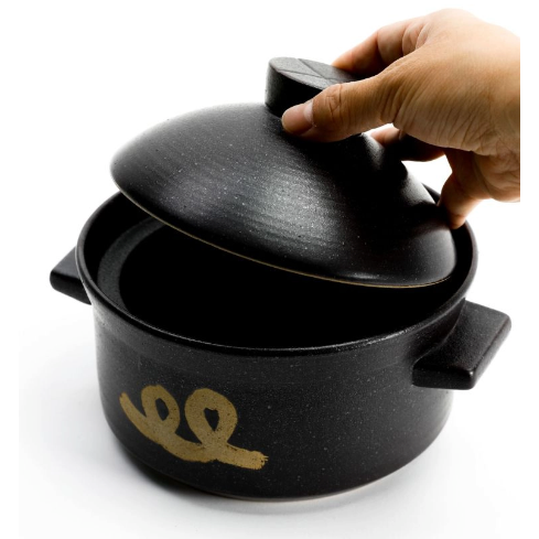 Black rice pot with lid, hand lifting the cover, gold emblem on front