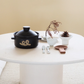 Black rice pot with lid and side handles on table, gold logo with small accessories