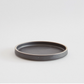Black mini ceramic plate with raised edge and smooth dark interior