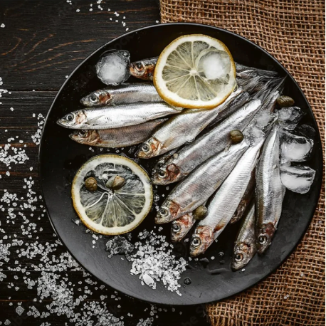 Silver fish assortment with lemon slices and ice crystals in a dark dish