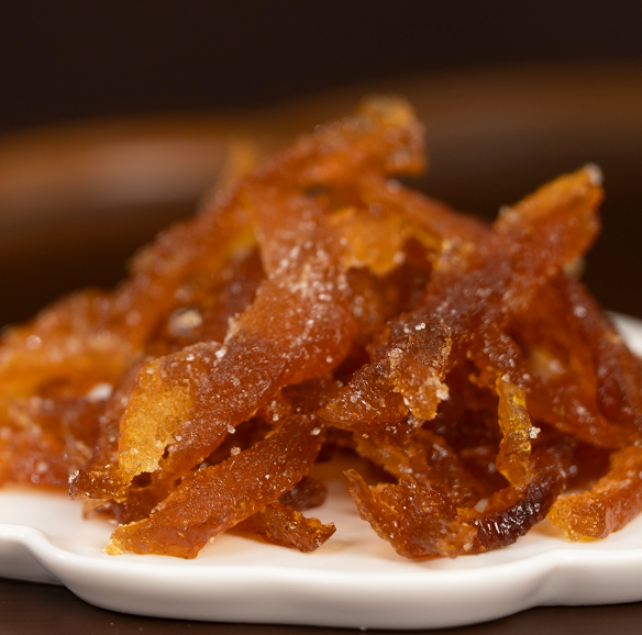 Close-up of orange candied yuja jelly strips on white dish