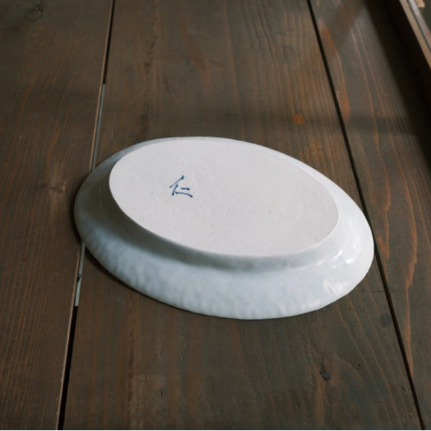 White oval serving plate with small blue mark on top surface