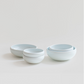 Stacked white ceramic one-person bowls set with smooth, rounded shape