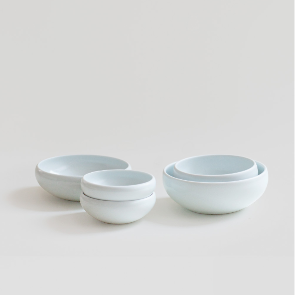 Stacked white ceramic one-person bowls set with smooth, rounded shape