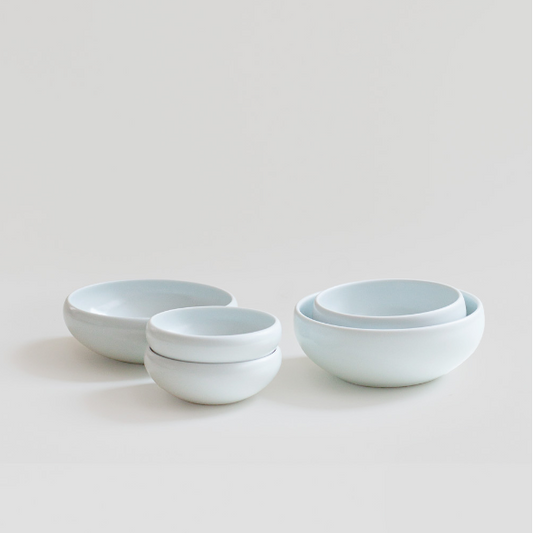 Stacked white ceramic one-person bowls set with smooth, rounded shape